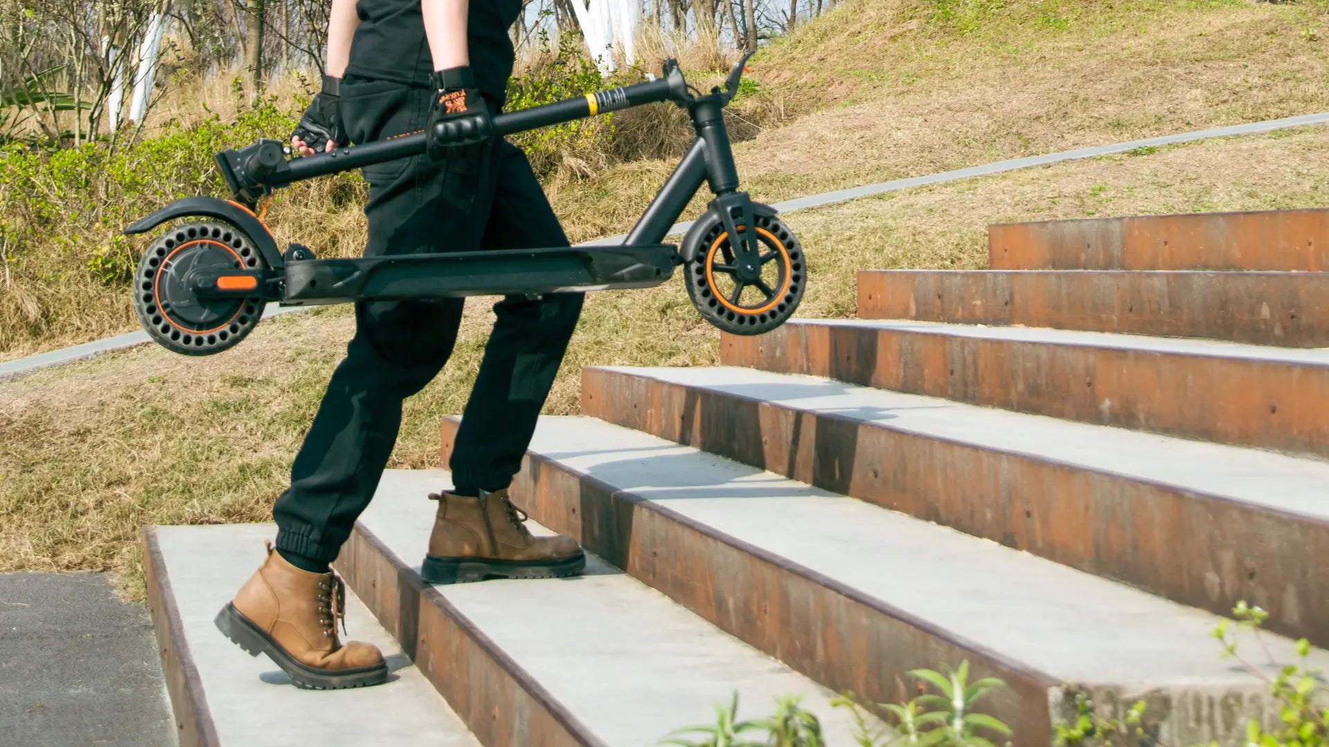 Folded KuKirin S1 Max electric scooter being carried up stairs, highlighting lightweight and portable design for daily commuting.